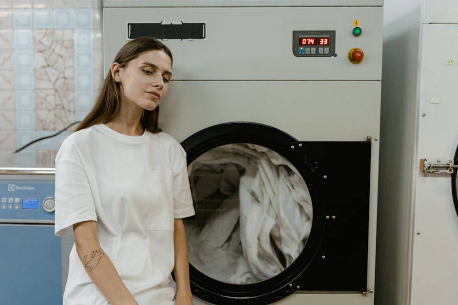 A professional cleaner from Hackney Wick Carpet Cleaners is engaged in surface cleaning within an indoor environment. The individual is dressed in a white protective coverall, a face mask, and orange 